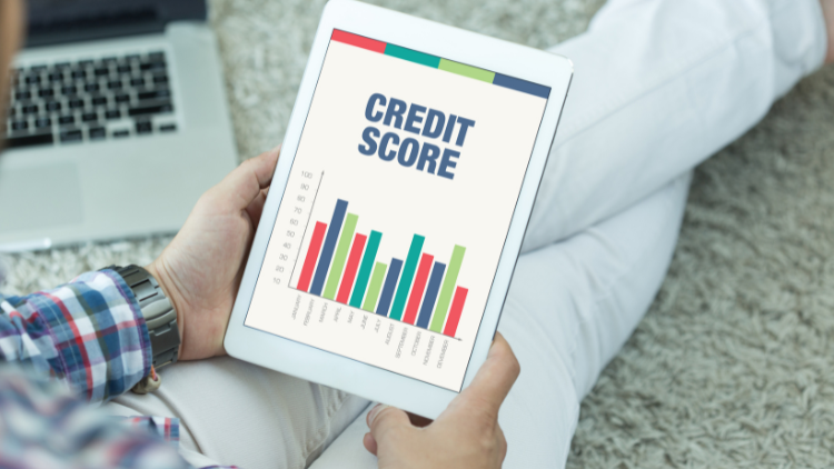 A man sitting on a carpet holding an iPad with the screen showing a bar graph of credit score ratings for each category.