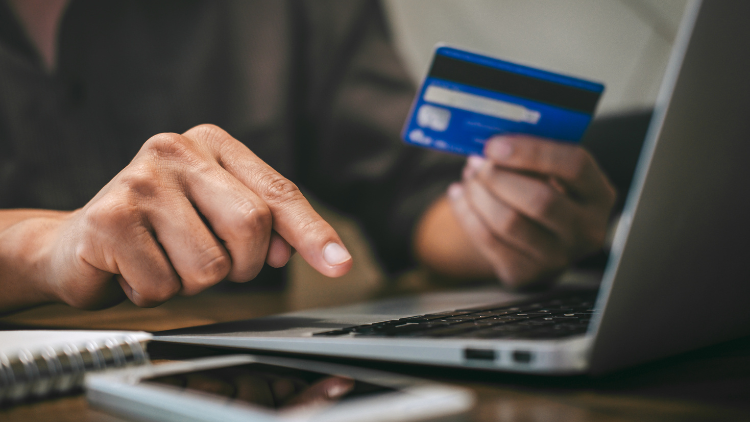 A person makes an online payment with a credit card and laptop, representing starter cards for building business credit.