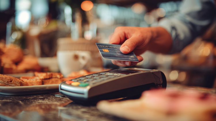 A customer makes a credit card payment at a point-of-sale terminal, showing how business credit cards are used for everyday transactions.