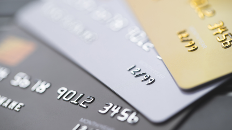 A detailed close-up shot shows three credit cards stacked on each other, with the numbers and expiration dates clearly visible.