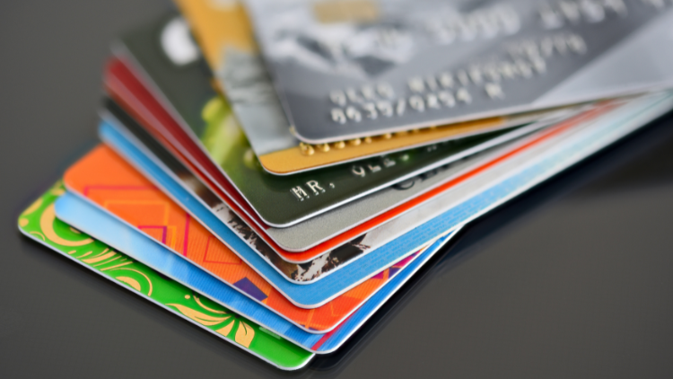 A close-up view of a fanned-out stack of colorful credit cards placed on a reflective surface.
