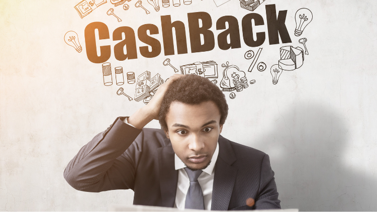 A man in a suit looks puzzled while sitting under a large cashback graphic.