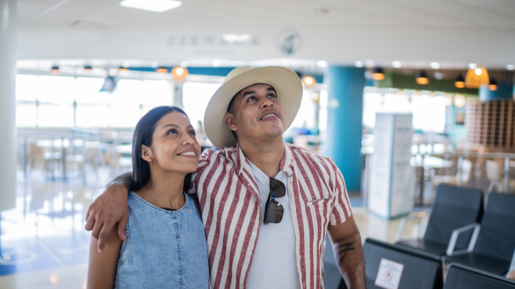 A cheerful couple embraces while walking through an airport terminal, excited about their upcoming trip.