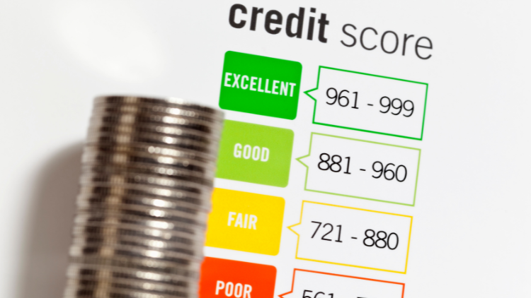 A close-up of a credit score chart showing ranges from poor to excellent beside a stack of coins.