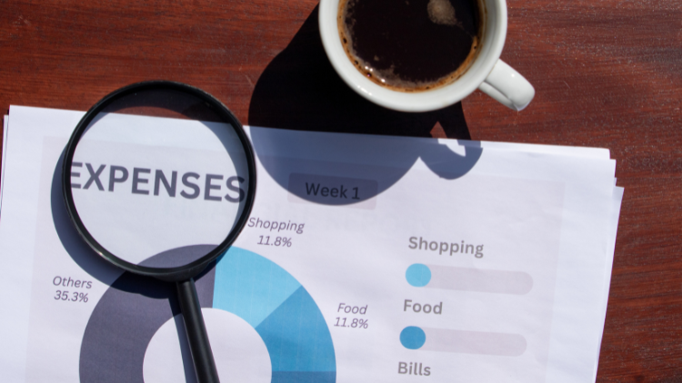 A magnifying glass and cup of coffee sit on top of a printed expense chart breaking down shopping, food, and bills.