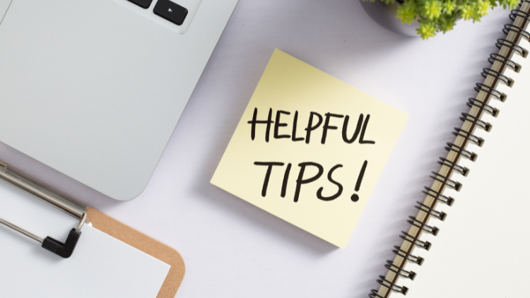 A sticky note reading "Helpful Tips!" sits on a desk next to a laptop, notebook, and plant.