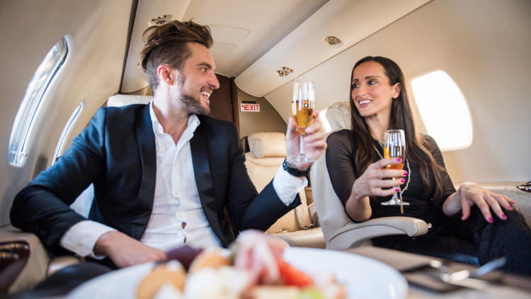 A stylish couple clinks glasses of champagne on a private jet, representing luxury travel earned through reward points.