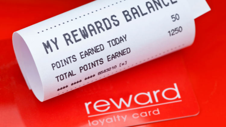 A printed receipt showing reward points balance and earnings placed on a red loyalty card background.