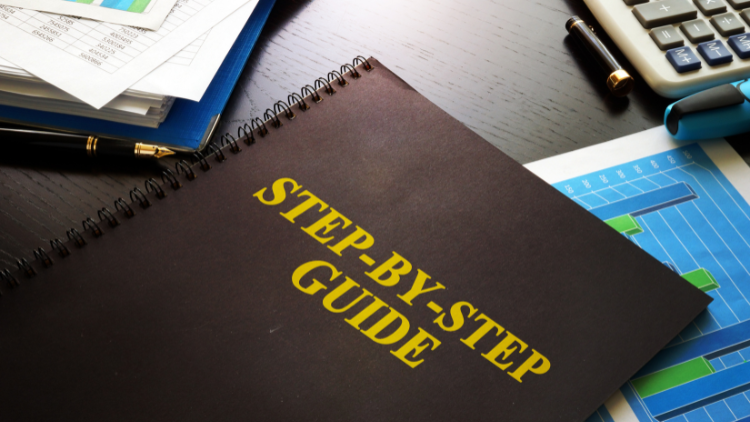 A black spiral-bound book titled “Step-by-Step Guide” lies on a desk surrounded by charts, papers, and a calculator.