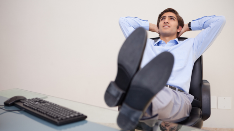A man leans back relaxed at his office desk, symbolizing confidence and peace of mind from organized financial planning.