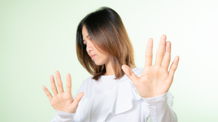 A woman in a white top raises both hands in refusal, symbolizing rejecting unfair credit card terms.